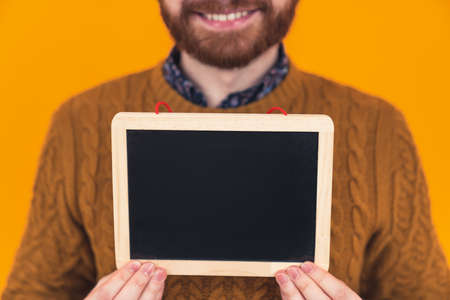 young caucasian man holding a small whiteboard in front of the camera. High quality photoの写真素材