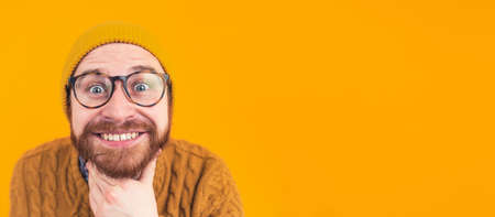 Headshot attractive young bearded Caucasian man looking at the camera, smiling, showing teeth isolated selective focus orange background studio shot copy space . High quality photoの写真素材