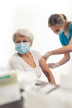 Vertical shot of caucasian elderly woman getting a vaccine booster to help out with stopping the pandemic. High quality photoの写真素材