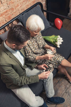 vertical photo of middle-aged caucasian man watching photographs with grandmother. High quality photoの写真素材