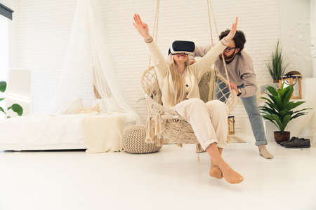 young Caucasian couple using virtual reality goggles spending free time together full shot copy space. High quality photoの写真素材
