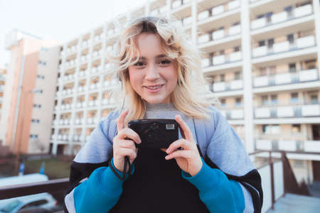Vintage photography concept. Beautiful European blonde-haired girl taking photos with her analog...