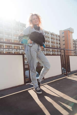 Cheerful caucasian woman in her 20s wearing 90s-inspired clothes and posing to camera with old mini cassette player. Vertical shot. . High quality photoの写真素材