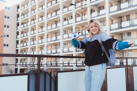 Hipster 90s-inspired caucasian girl enjoying music on headphones and cassette player dancing in her...
