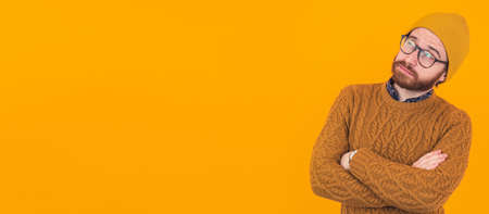 Handsome Caucasian man looking away with interest crossing hands orange background copy space isolated studio shot . High quality photoの写真素材