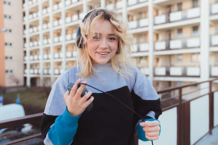 Smiley caucasian blonde-hared young woman listening to her favorite album on cassette player....