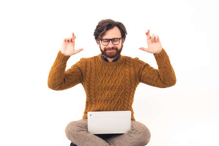 Young handsome Caucasian man with glasses keeping his hands up and having fingers crossed, eyes closed brown knitted sweater medium shot isolated white background . High quality photoの写真素材