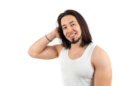 Handsome European bearded man with long hair looking at camera and smiling while wearing white tank top. Isolated medium studio shot over white background. High quality photoの写真素材