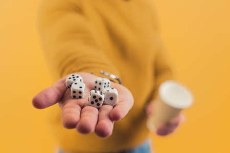 Five dice lying on a hand of a caucasian person. Studio shot over yellow background. High quality photoの写真素材
