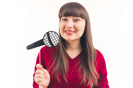 Studio portrait of smiley positive caucasian woman in her 20s holding fake paper microphone and looking at camera. High quality photoの写真素材