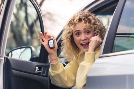 Excited blond woman shown car keys to the camera siting in her new car emotions portrait copy space...