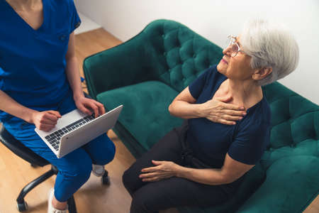 Caucasian female doctor has a home visit with her elderly grey-haired patient. High quality photoの写真素材