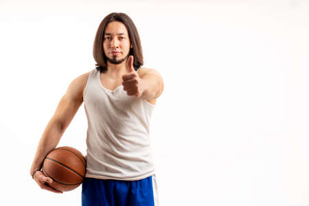 Athletic muscular caucasian basketball player showing thumbs up to the camera while holding...