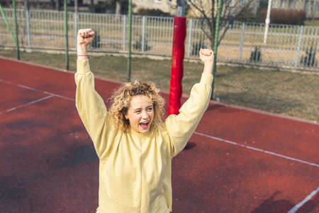 Excited young blond hipster woman celebrates her victory after throwing the basketball ball into the...