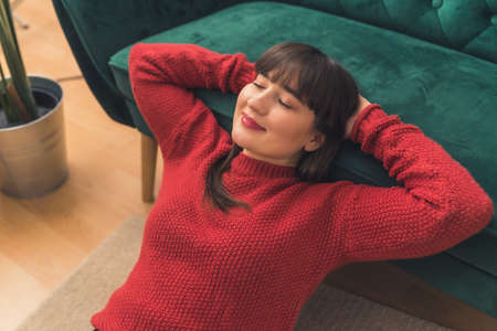 Well-being concept. Young millennial woman taking break from stressful job by relaxing and leaning back on sofa. High quality photoの写真素材