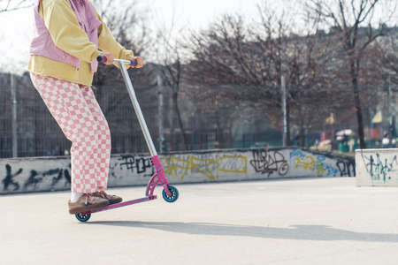 Young European woman drives a pink scooter on the skateboard ground active lifestyle concept no face visible copy space full shot . High quality photoの写真素材