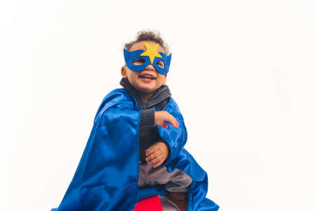 little African American curly boy with the blue costume of superhero laughing full shot studio shot white background copy space. High quality photoの写真素材