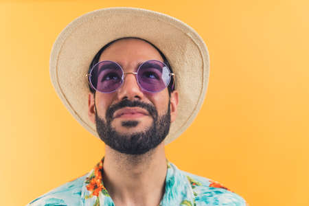 attractive Latin man in casual summer clothes waiting for summer vacation concept studio shot medium closeup orange background. High quality photoの写真素材