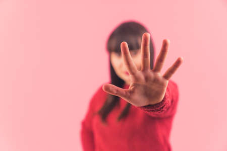 Young dark-haired Caucasian woman showing five fingers to the camera, focus is on the hand pink background isolated studio shot medium closeup copy space . High quality photoの写真素材