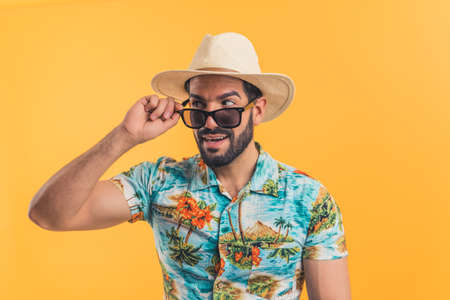 young bearded Latin American man in beach clothes looking sideways orange background medium closeup vacation concept. High quality photoの写真素材