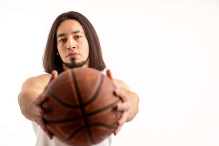Serious confident caucasian man holding basketball ball to the camera. Isolated studio shot over white background. High quality photoの写真素材