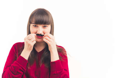 Movember - millennial woman imitates moustache with her hair white background isolated copy space portrait . High quality photoの写真素材
