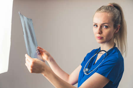Professional female healthcare worker looks at camera and holds chest x-ray belonging to her patient. . High quality photoの写真素材