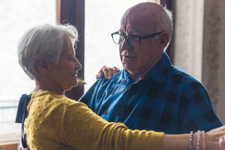 Joyful active old retired caucasian couple dancing in their living room. Closeup indoor shot. High...