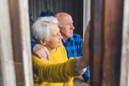 European retired senior heterosexual couple looking peacefully out of the window and thinking about their future. Tranquil retirement concept. High quality photoの写真素材