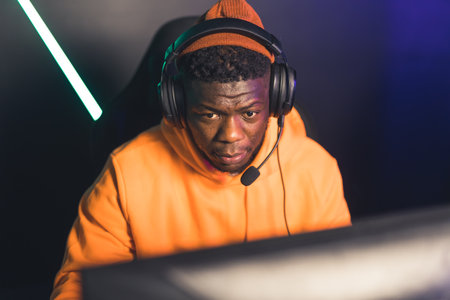 Gamer club. African-American focused male gamer in a yellow hoodie and professional headset. Online competition concept. High quality photoの写真素材