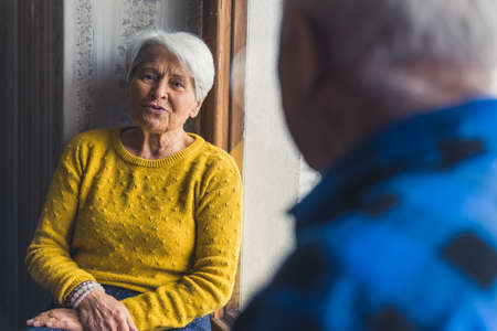 lovely senior couple talking to each other on a window-sill medium shot indoors senior people...