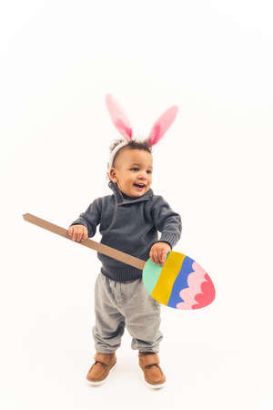 Small child holding cartoon Easter egg and wearingbunny ear looks happy and excited, fuul length. High quality photoの写真素材