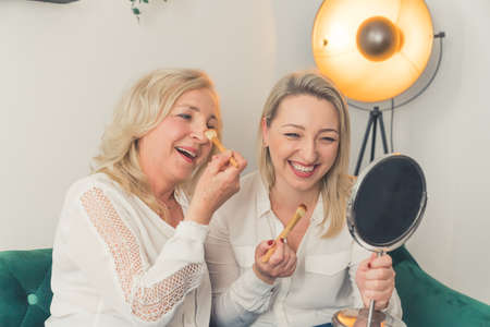 Smiling millennial girl child with overjoyed funny elderly mother at home, happy grown-up adult daughter have fun making up with mom, relax together on weekend. High quality photoの写真素材