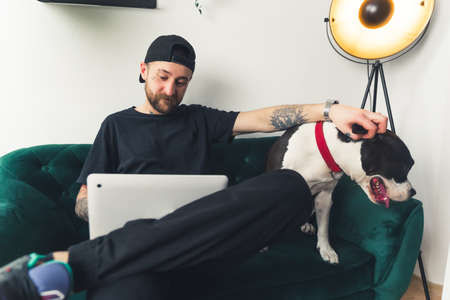 American Staffordshire Terrier and his owner sitting together on a couch in a modern apartment and enjoy their leisure time. High quality photoの写真素材