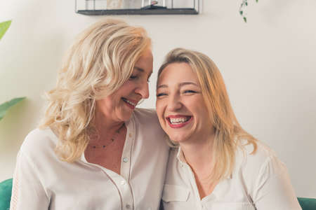 Happy mature mother and grown-up adult daughter smiling together, portrait. High quality photo
