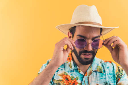 Latin handsome man putting on his violet sunglasses . High quality photo