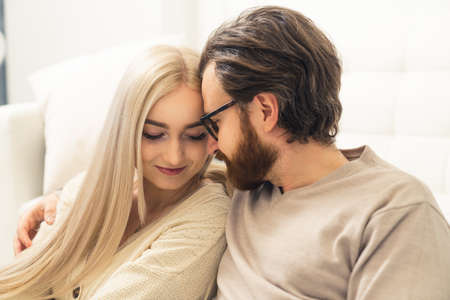 Smiling lovely caucasian spouses sitting at home hugging each other affectionately. Close up indoor shot. High quality photoの写真素材