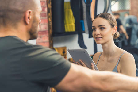 Beautiful Caucasian woman writes down a workout plan with a trainer at the gym. High quality photoの写真素材