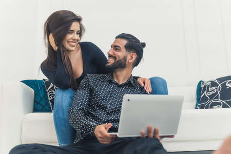 Adult couple using laptop and smiling while sitting at home, romantic mood. High quality photoの写真素材