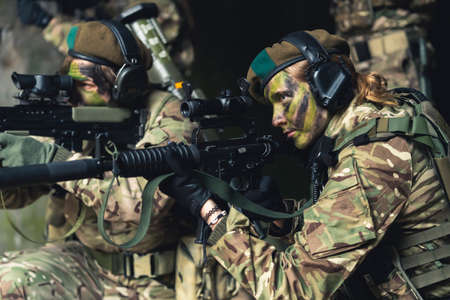 Two soldiers with camouflage painted on their faces aiming at a target. High quality photoの写真素材