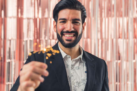 Joyful Lating American male holding bengal light in hand smiling camera, office party. High quality photoの写真素材