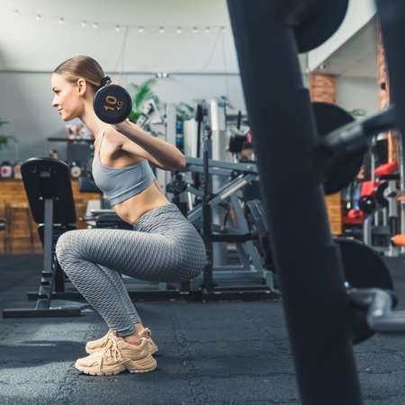 Sporty woman doing weight squats at the gym, vertical. High quality photoの写真素材