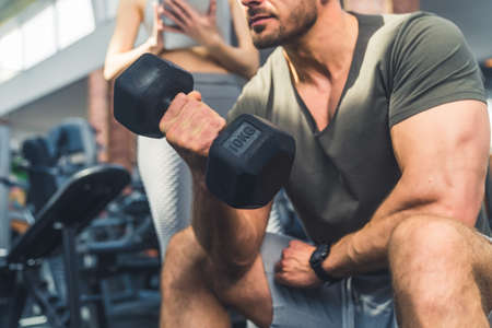 Muscular young man lifting weights indoor at the gym, close-up photo. High quality photoの写真素材