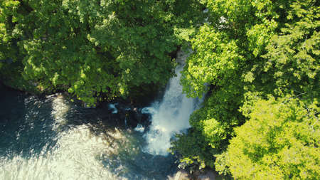 birds-eye view of green forest and small cute waterfall in its depth, aerial. High quality photoの写真素材