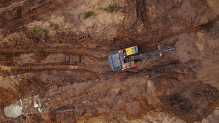 Aerial view of an excavator digging up the road on a construction site - copy space. High quality...