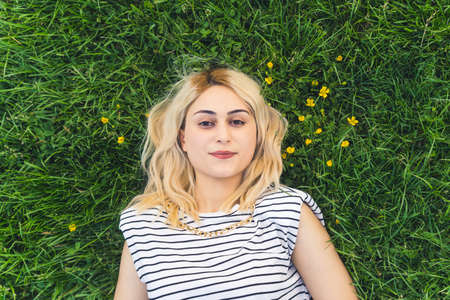 pretty blond girl resting on the green grass. medium closeup. High quality photoの写真素材