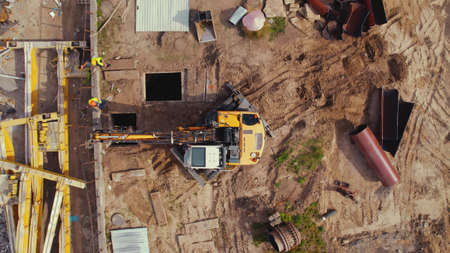Aerial shot of a construction site. Workers dressed in high-visibility jackets supervising the work...