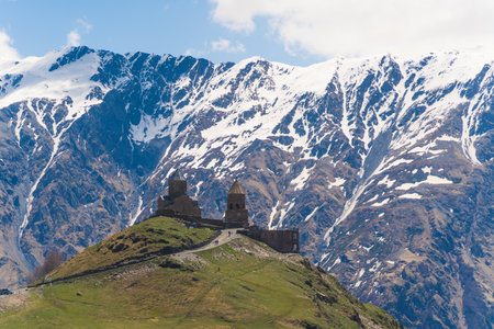 beautiful view of ancient Gergeti Trinity Church in Kazbegi, Georgia. snow-capped Caucasus mountains in the background. High quality photoの写真素材