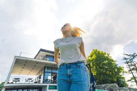 blonde Caucasian girl from below looking besides. cowboy shot outdoor urban. High quality photoの写真素材