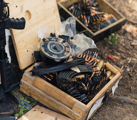 Square outdoor shot of two wooden boxes filled with ammunition and other accessories for firearm....